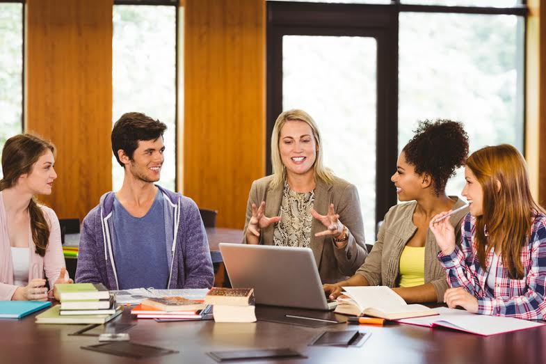 Smiling students and teacher in library at a small college